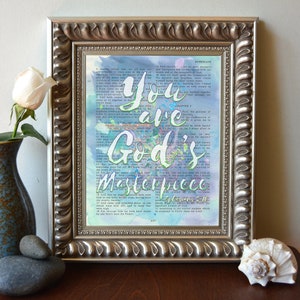 May include: A framed print with a watercolor background and the text "You are God's Masterpiece" in green and white lettering. The background is a vintage bible page.