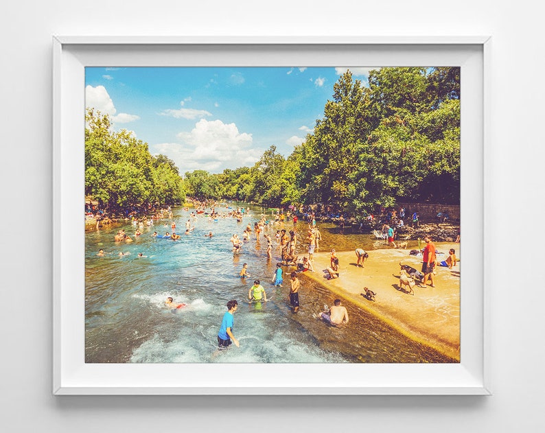 K&ouml;nnte beinhalten: Ein sonniger Tag an einem Fluss, auf dem Menschen schwimmen und im Wasser spielen. Der Fluss ist von B&auml;umen umgeben und auf der rechten Seite des Bildes befindet sich ein Sandstrand.