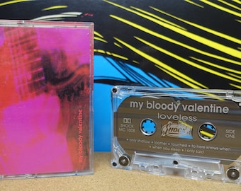 May include: A clear plastic cassette tape case with a black cassette tape inside. The cassette tape has the text "my bloody valentine loveless" printed on it. The cassette tape is labeled "Shock MC 1008" and "Side One".