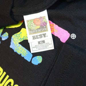 May include: Black t-shirt with colorful text that reads "RESIST DRUGS VIOLENCE". The shirt has a Fruit of the Loom tag that says "BEST" and "XL". The shirt has a colorful design.