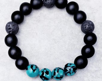 Pode incluir: Pulseira de contas pretas e turquesa com contas de lava. A pulseira tem um design simples e é feita com pedras naturais.