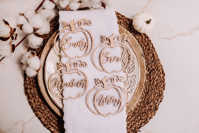 Thanksgiving decor idea featuring personalized pumpkin name signs made of laser-cut wood. Great for organizing your holiday seating arrangement with style, while offering guests a small, thoughtful favor to remember the event.