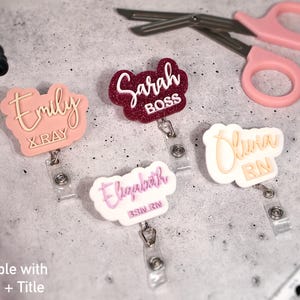 Two-line custom acrylic badge reels with name and title engraving such as RN, BSN, and X-RAY. Personalized retractable ID holders for nurses, doctors, and medical staff. Features 360° alligator clip and retractable cord up to 25 inches. Shown in blush, glitter red, and white pastel combinations. Perfect nurse week gift or custom name badge reel for healthcare professionals.