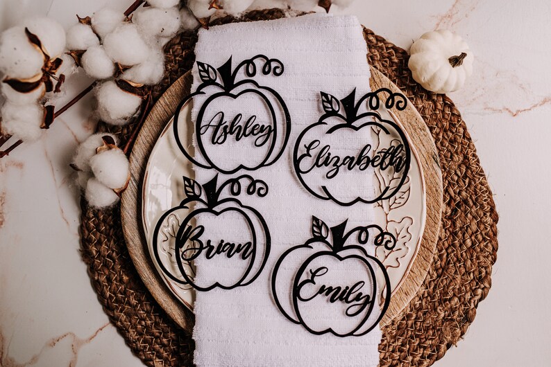 Custom name tags shaped like pumpkins for Thanksgiving table decorations. These wood or acrylic place cards are engraved with guest names and come in five finish options, making them a perfect fit for holiday dinners or festive events.
