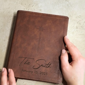 Close up of personalized wedding Bible engraving showing script last name and block established date on leather NIV Bible cover. Custom family Bible guest book for wedding ceremony, Christian gift for bride and groom.