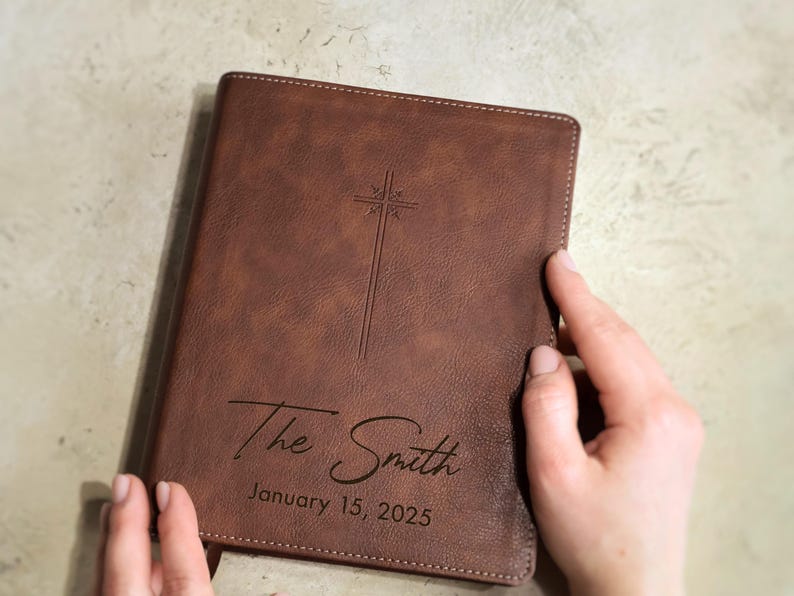 Close up of personalized wedding Bible engraving showing script last name and block established date on leather NIV Bible cover. Custom family Bible guest book for wedding ceremony, Christian gift for bride and groom.