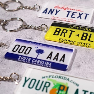 Replica license plate keychain customized with any text or initials. Realistic plate details make it a fun conversation starter and practical car key holder. Crafted from glossy acrylic for a durable, lightweight finish. Perfect personalized gift for drivers, car fans, and road-trip lovers. A collectible item that celebrates your favorite state or custom message.