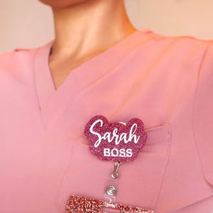 Custom acrylic badge reel with name and title “Boss” worn on scrubs. Personalized retractable ID holder with glitter acrylic finish, 360° rotating alligator clip, and smooth pull cord. Nurse badge reel gift for medical professionals, CNAs, or managers. Elegant handcrafted acrylic design, perfect nurse week or office gift.