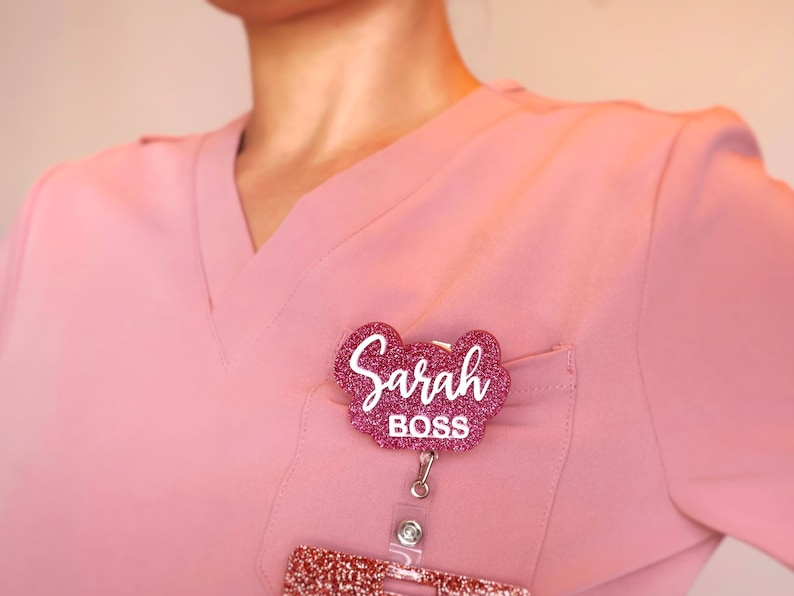 Custom acrylic badge reel with name and title “Boss” worn on scrubs. Personalized retractable ID holder with glitter acrylic finish, 360° rotating alligator clip, and smooth pull cord. Nurse badge reel gift for medical professionals, CNAs, or managers. Elegant handcrafted acrylic design, perfect nurse week or office gift.