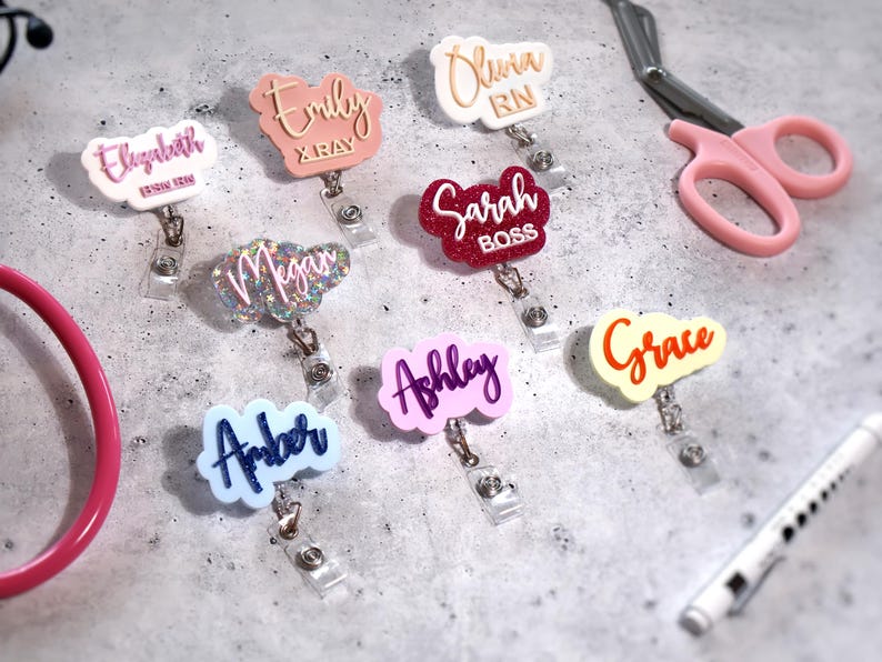 Custom name badge reel set featuring personalized acrylic name tags for nurses, teachers, and office staff. Retractable ID holders with 360° alligator clips in pastel, glitter, and mirrored finishes. Shown with names Grace, Ashley, and Olivia. Perfect nurse badge reel gift or hospital ID clip, handcrafted from durable acrylic for everyday use. Nurse week or coworker gift idea, custom retractable ID holder USA made.