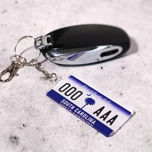 Custom license keychain inspired by classic U.S. plates. Create your own replica design with personalized text. Ideal for car enthusiasts, mechanics, or travel lovers. Lightweight acrylic key tag with realistic details makes it a standout accessory. Great driver’s gift, car key decoration, or creative souvenir for anyone who appreciates custom automotive style.