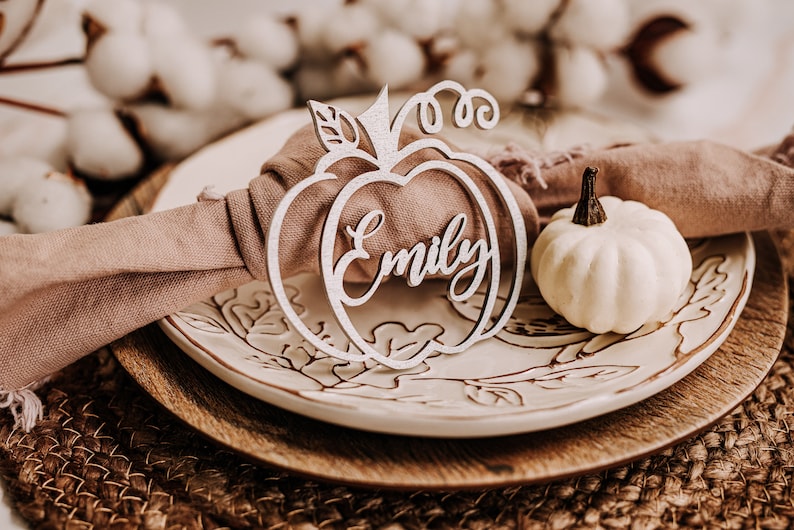 Handcrafted fall pumpkin name signs used as custom place cards for Thanksgiving dinner or Friendsgiving parties. Available in raw wood, gold, silver, black, white, orange, peach, glitter gold, black, copper or mirrored gold acrylic, adding warmth and personalization to your seasonal table decor.