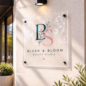 Custom square acrylic business sign with full-color UV printed logo and silver mounting hardware displayed behind a modern reception desk