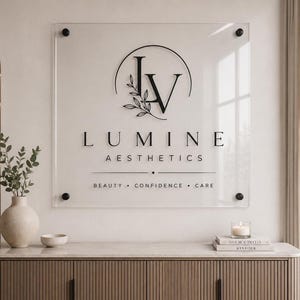 Personalized clear acrylic office sign featuring a black company logo and black standoff mounts in a professional reception area.
