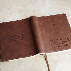 Wedding guest book Bible displayed open with guests signing inside pages. Personalized NIV leather family Bible used as alternative wedding guestbook for religious wedding reception and Christian ceremony decor.