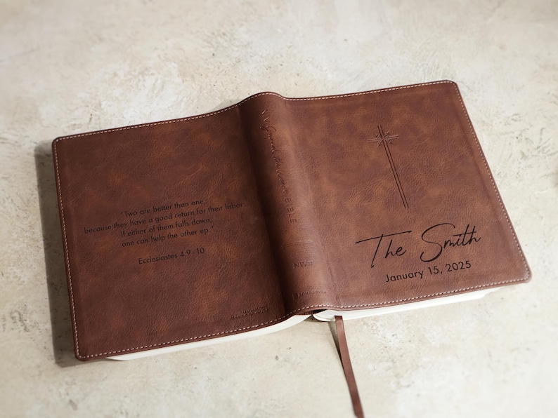 Wedding guest book Bible displayed open with guests signing inside pages. Personalized NIV leather family Bible used as alternative wedding guestbook for religious wedding reception and Christian ceremony decor.