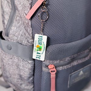 Personalized state license plate keychain featuring your chosen U.S. state and custom text. Printed in vibrant color on durable acrylic for a realistic look. Great for drivers, new car owners, or auto enthusiasts. Use it as a keychain, bag tag, or small travel gift. A creative and thoughtful car accessory for anyone who loves unique personalized keychains.