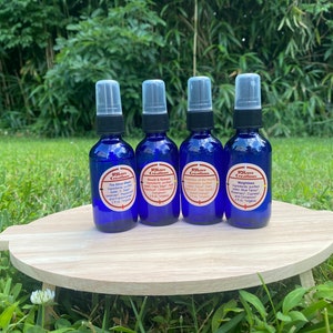 May include: Four small blue glass bottles with spray tops, each containing a different essential oil blend. The bottles are labeled with the brand "Rillow Creations" and the names of the blends: "The Silver Blue", "Breath & Renew", "Angles of the Beach", and "Weightless".