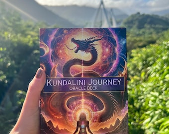 May include: A blue and purple oracle deck box with a colorful illustration of a dragon and a person meditating. The box has the text "Kundalini Journey Oracle Deck" and "Stephanie Fleitas" on it.