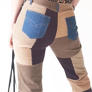 Op de afbeelding: Patchwork corduroy broek in bruin-, beige- en paarse tinten met denim zakken. De broek heeft een uitlopende pijp en wordt gedragen met een top met luipaardprint en sandalen met hakken. Een zwarte schoudertas hangt aan de linkerkant.