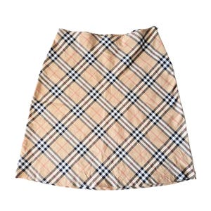 May include: A beige plaid skirt with a classic pattern. The skirt features a repeating pattern of tan, black, white, and red lines. The skirt is a-line and appears to be made of a lightweight fabric.
