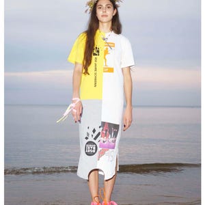 May include: A color-blocked dress with a yellow, white, and gray design. The top half is split between yellow and white, with printed graphics. The bottom half is gray with graphic prints. The person is wearing a floral crown and pink sandals.