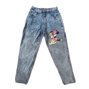 May include: Light blue acid wash denim jeans with a cartoon image of Mickey Mouse and Minnie Mouse on the right leg.