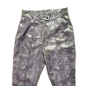 Op de afbeelding: Paarse en grijze broek met slangenprint, hoge taille en knoopsluiting.