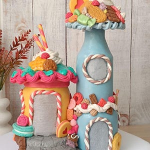 Puede incluir: Una linterna artesanal con forma de casa de caramelos en amarillo y azul, adornada con caramelos, galletas y una fresa. El texto "Candy House Lantern Handmade Fantasy Decor" es visible.