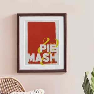 Könnte beinhalten: Ein gerahmter Druck mit rotem Hintergrund und weißem Text, der in gelben Buchstaben "& PIE MASH" lautet.
