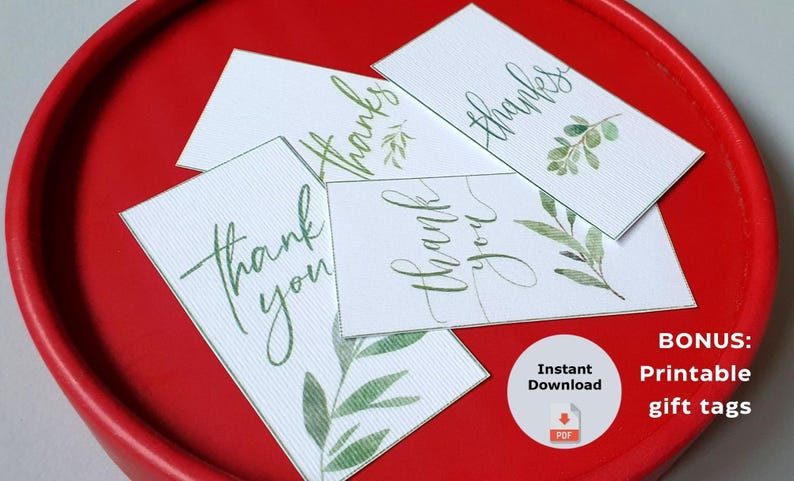 Puede incluir: Etiquetas de regalo blancas con escritura verde que dice "gracias" y "gracias", con acentos de hojas de acuarela. Las etiquetas est&aacute;n dispuestas en una bandeja roja. La imagen tambi&eacute;n incluye un icono de etiqueta de regalo imprimible de bonificaci&oacute;n.