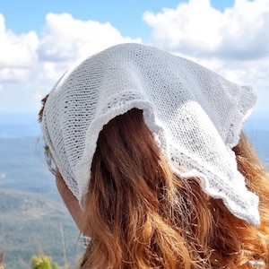 May include: A white triangular headscarf crafted from a fine-knit fabric with a delicate, scalloped edge. The headscarf features a subtle, textured stitch pattern throughout, providing a lightweight and breathable appearance for versatile wear.