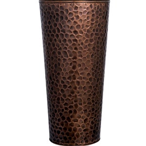 May include: A hammered copper planter with a textured surface. The planter is a cylindrical shape with a wide opening at the top and a narrow base.