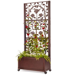 May include: A brown metal garden trellis with a planter box on wheels. The trellis features a decorative floral design and is adorned with climbing plants with red flowers.