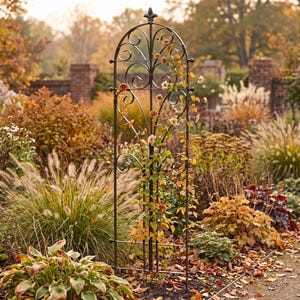 May include: A tall, black metal garden trellis with an arched top and a decorative finial. The structure features vertical bars and symmetrical scrollwork patterns. A climbing plant with green leaves and small orange flowers grows up the frame.