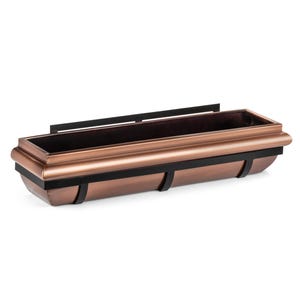 May include: A copper window box planter with black metal brackets. The planter has a rounded, slightly curved shape and a decorative lip around the top.
