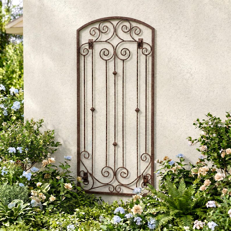 Pu&ograve; includere: Un alto traliccio da giardino in metallo ad arco con una finitura marrone anticata. La struttura presenta barre verticali arricchite da piccole sfere decorative e intricati motivi a volute nella parte superiore e inferiore.