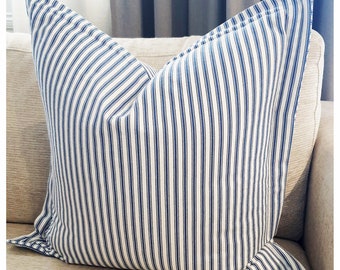 May include: A white and blue striped throw pillow with a square shape. The pillow is made of a soft, woven fabric and has a subtle sheen.