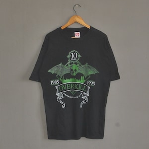 May include: Black t-shirt with a green graphic of a skull with wings and the text "Overkill" with the years 1985 and 1995 on either side. The graphic also includes the text "Wrecking Your Neck".