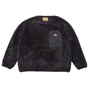 May include: A black fleece pullover sweatshirt with a zippered pocket on the left side. The pocket has a small triangle logo on it.