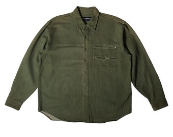 May include: A green long-sleeved button-down shirt with a single chest pocket and a small label that reads "FULL COUNT" on the collar.