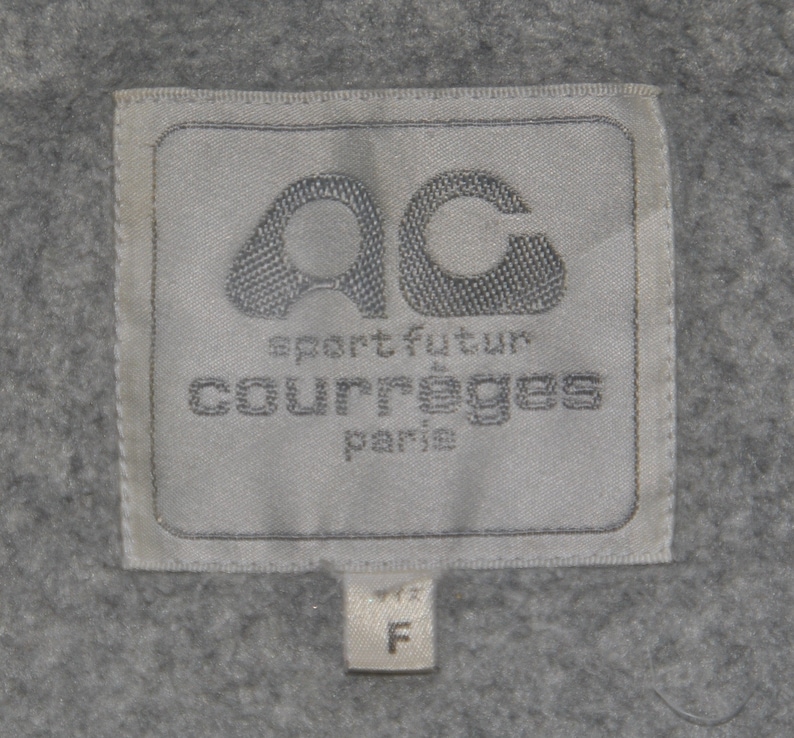 Puede incluir: Etiqueta blanca con texto negro que dice "AC sport futur Courr&egrave;ges Paris" y una etiqueta de talla que dice "F".