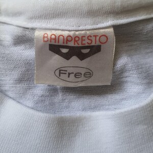 May include: White t-shirt with a Banpresto label featuring a black mask logo and the word "Free" in a circle.