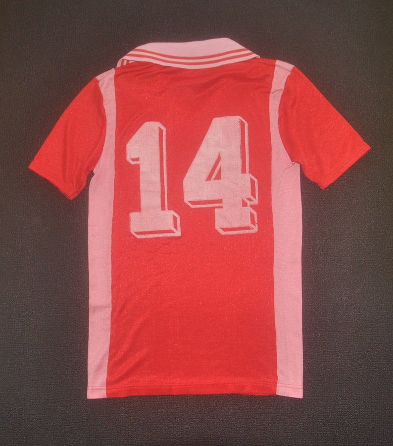 Op de afbeelding: Rood voetbal shirt met roze accenten en het nummer 14 gedrukt op de rug.