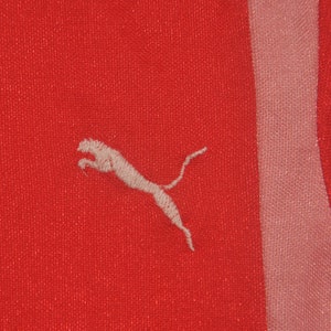 Op de afbeelding: Een rood en roze sporttrui met een wit Puma-logo geborduurd op de voorkant.