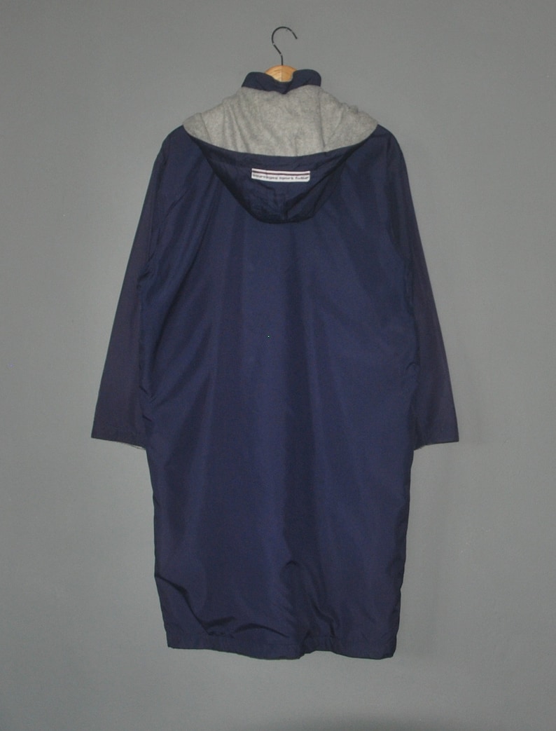 Puede incluir: Una chaqueta azul marino con capucha y forro de polar gris. La chaqueta tiene cierre de cremallera y capucha con cord&oacute;n. La etiqueta de la chaqueta dice "Champion Sportswear"