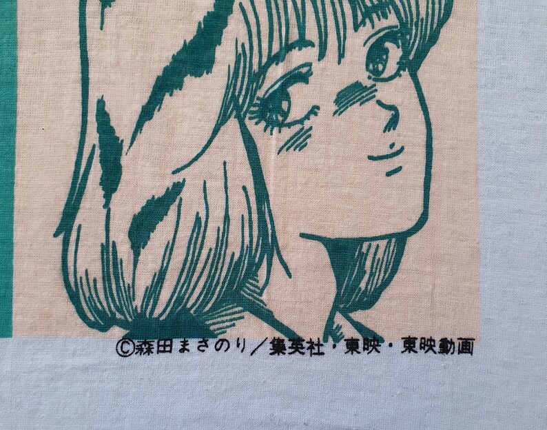 May include: A white t-shirt with a green line drawing of a woman with long hair. The text "&copy;森田まさのりの/集英社・東京・東映動画" is printed on the bottom of the shirt.