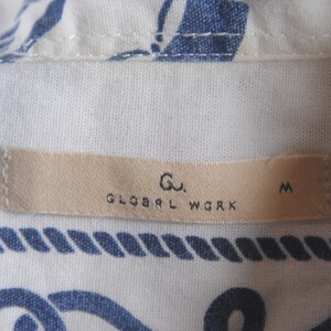 May include: A beige clothing tag with the text "Gu. GLOBAL WORK M" printed in black.