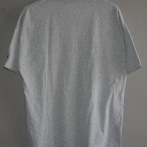 Op de afbeelding: Een grijs T-shirt met korte mouwen en een ronde hals. Het T-shirt heeft een klein logo op de linkermouw.