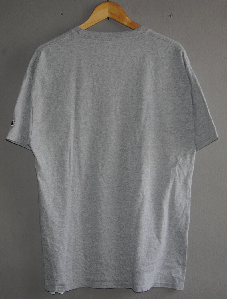 Op de afbeelding: Een grijs T-shirt met korte mouwen en een ronde hals. Het T-shirt heeft een klein logo op de linkermouw.